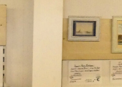 Panorama-Foto der Miniatur Gemälde Ausstellung im ersten Stock des "Möbel & mehr" Gebrauchtwarenkaufhauses Kitzingen Lochweg 22. 34 Gemälde reihen sich Seite an Seite mit Infobeschilderung und Preisangabe nebeneinander, darunter zahlreiche verschiedene Stilrichtungen und bekannte Maler- und Künstler:innen.